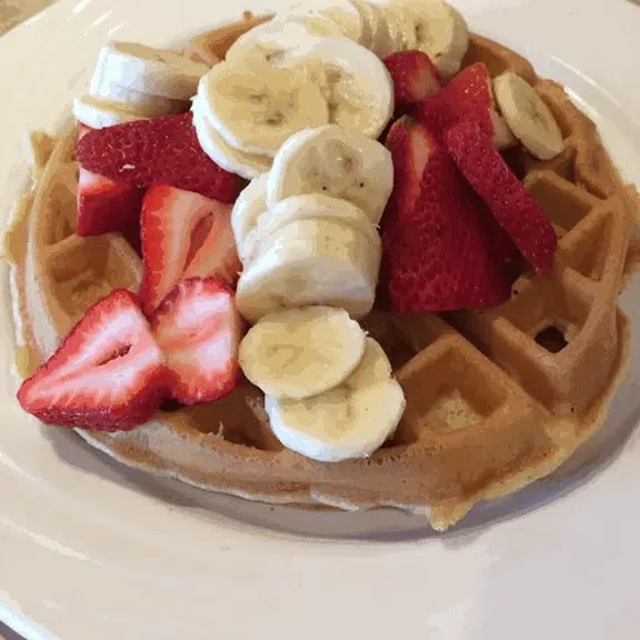 Belgian waffle topped with fresh strawberries and banana slices
