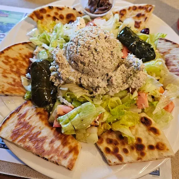Fresh garden salad topped with grilled chicken and pita bread